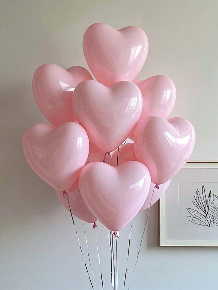 Bouquet de ballons cœurs rose pâle devant un mur blanc