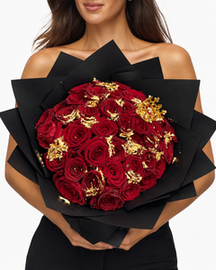 24 CARATS, bouquet de roses éternelles rouges avec feuilles d'or et emballage noir, tenu à la main