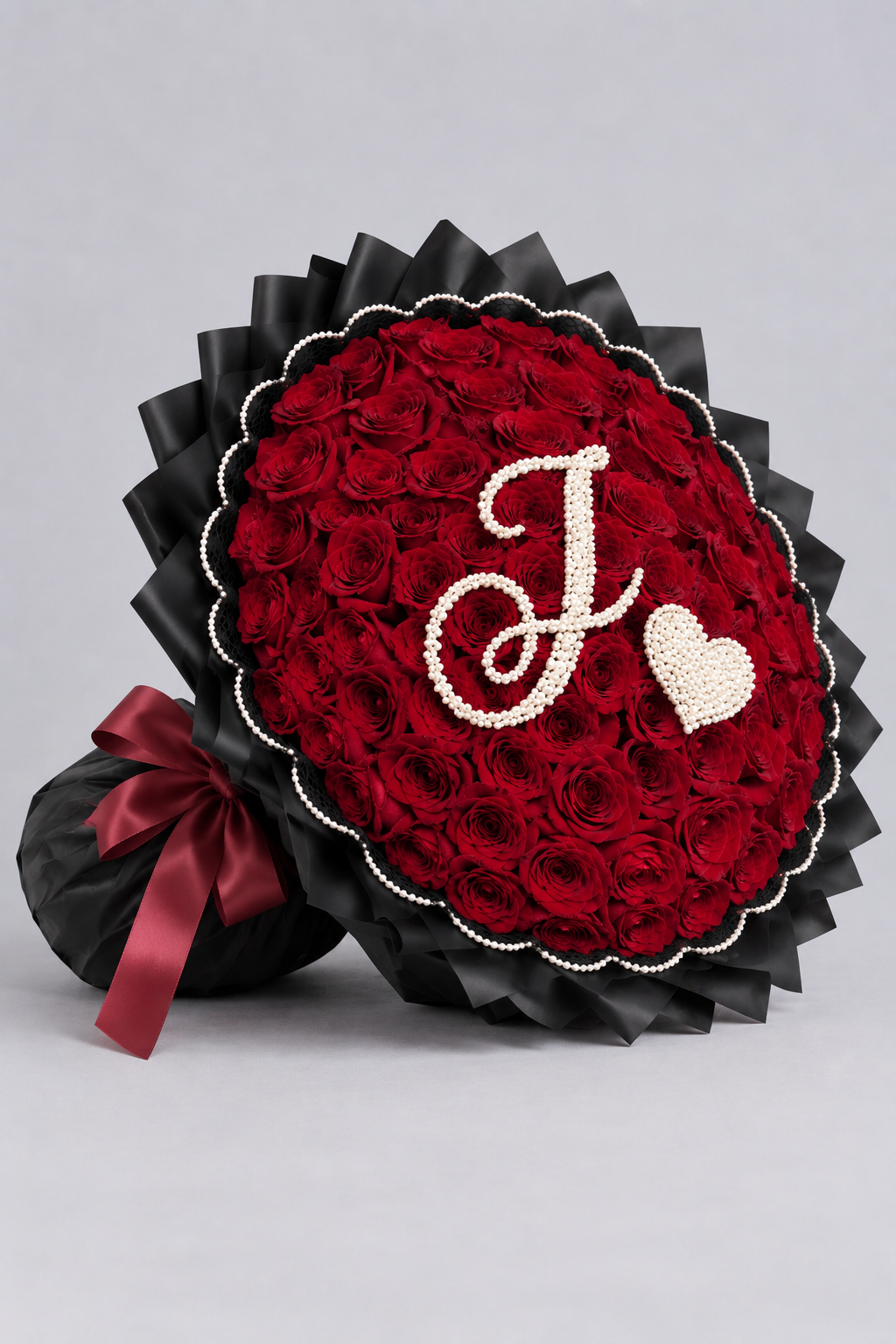 Bouquet Ava de roses rouges fraîches, vue de côté avec papier noir plisse et ruban rouge