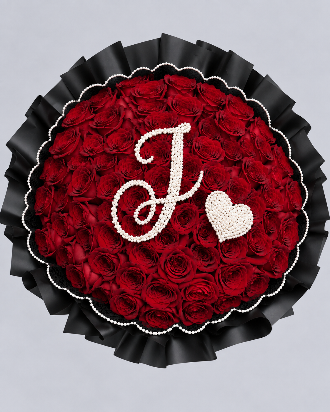 Bouquet Ava de roses rouges fraîches vu de dessus avec lettre J et cœur en gypsophile, fond gris