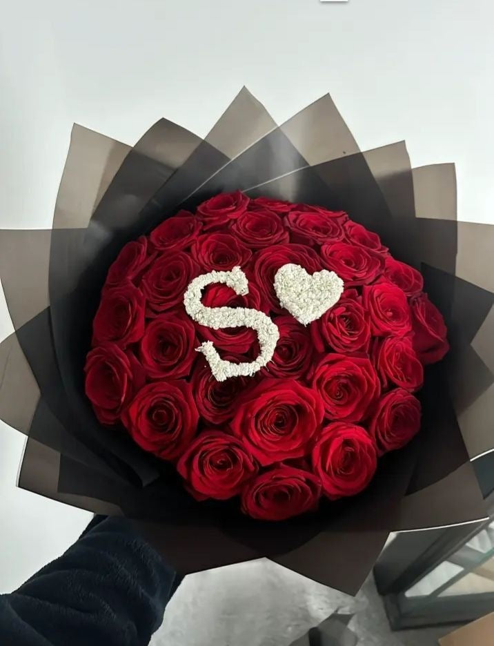Bouquet Ava de roses rouges fraîches avec lettre S et cœur en gypsophile, papier noir transparent