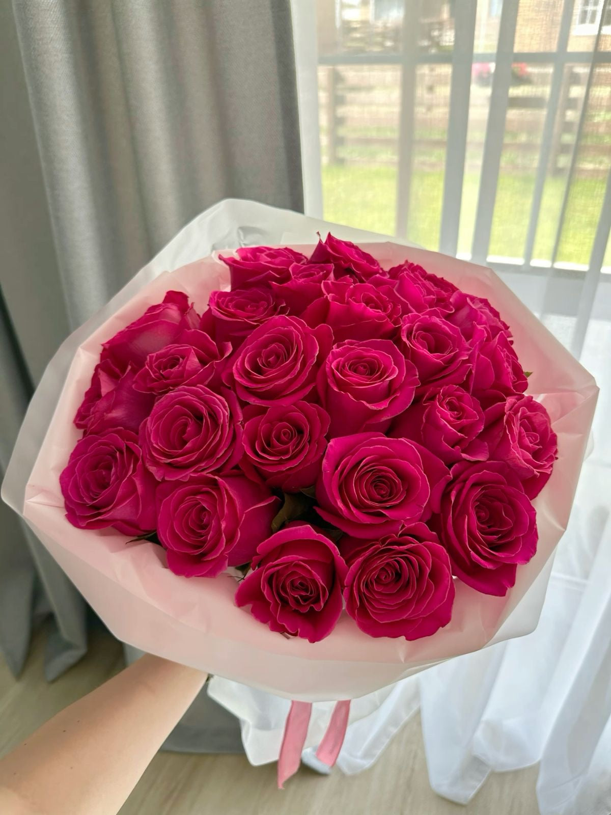 Petit bouquet Bella d'environ 20 roses fraîches tenu en main, papier rosé