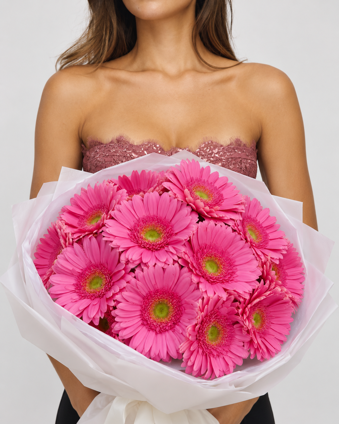 Bouquet Alinea de gerberas roses frais en papier blanc, tenu devant soi