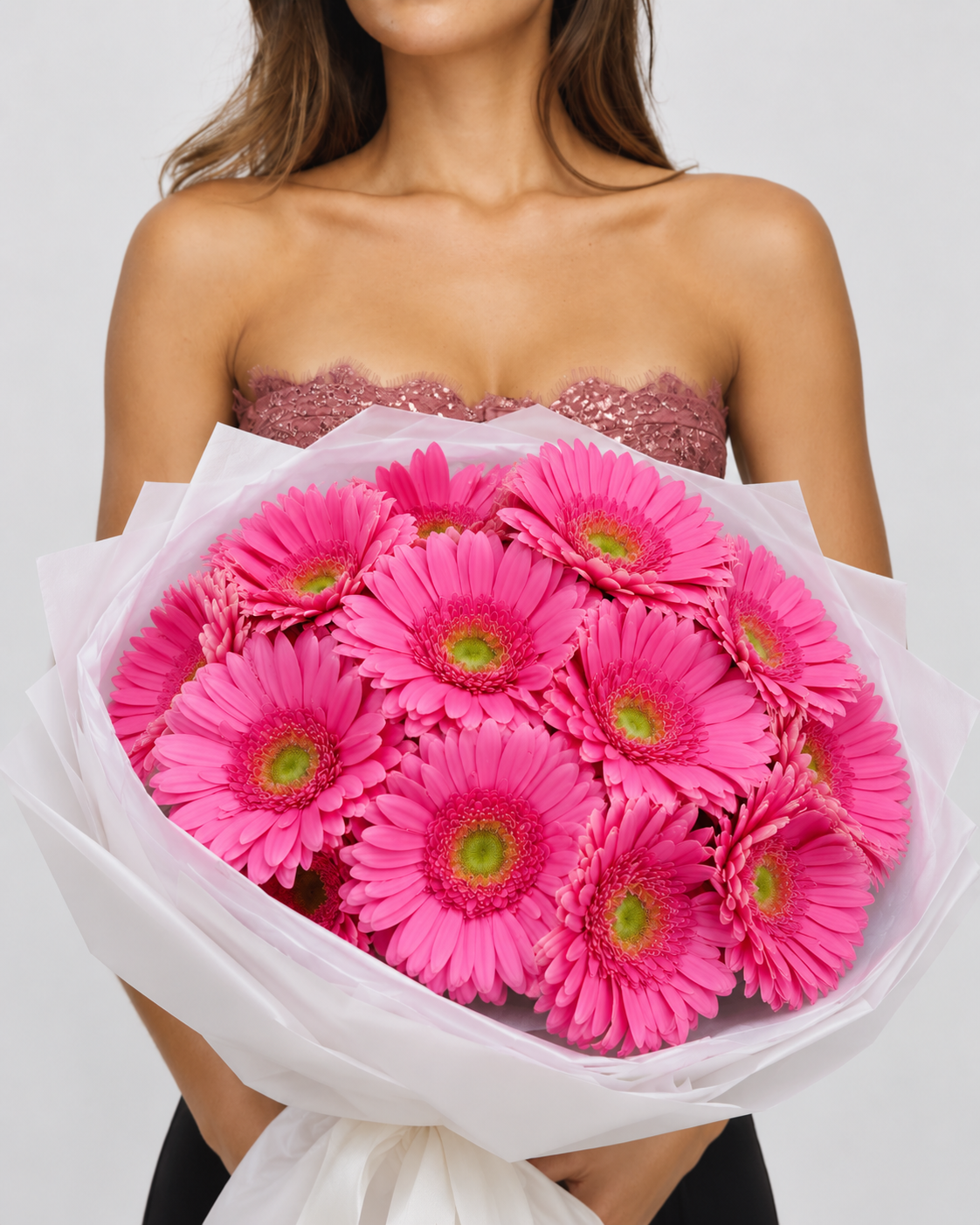 Bouquet Alinea de gerberas rose vif tenu à deux mains, papier blanc translucide