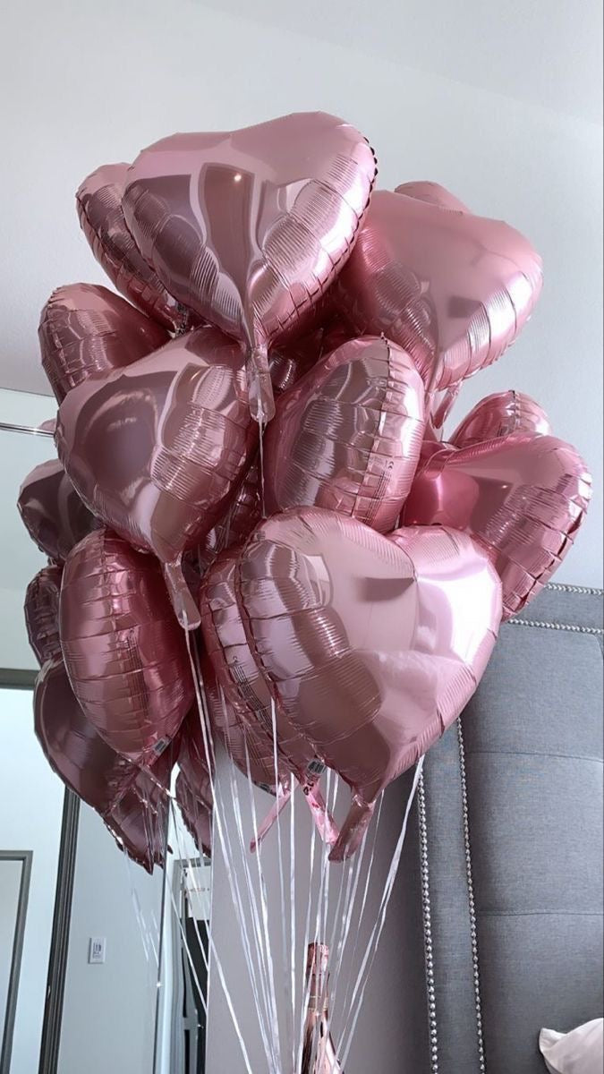 Bouquet de ballons cœurs rose poudré flottant dans une pièce