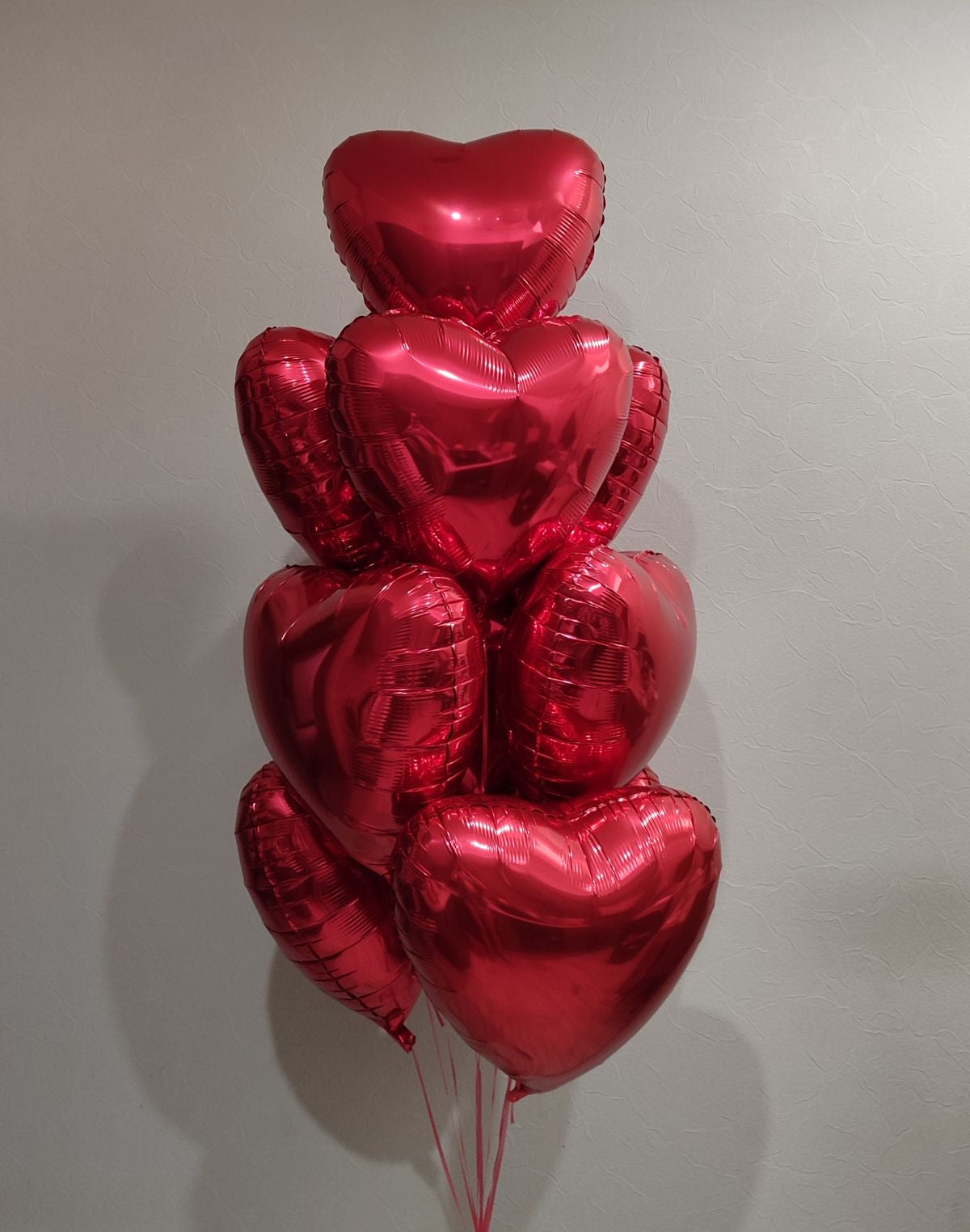 Bouquet de ballons cœur rouges love flottant au mur, photo réelle