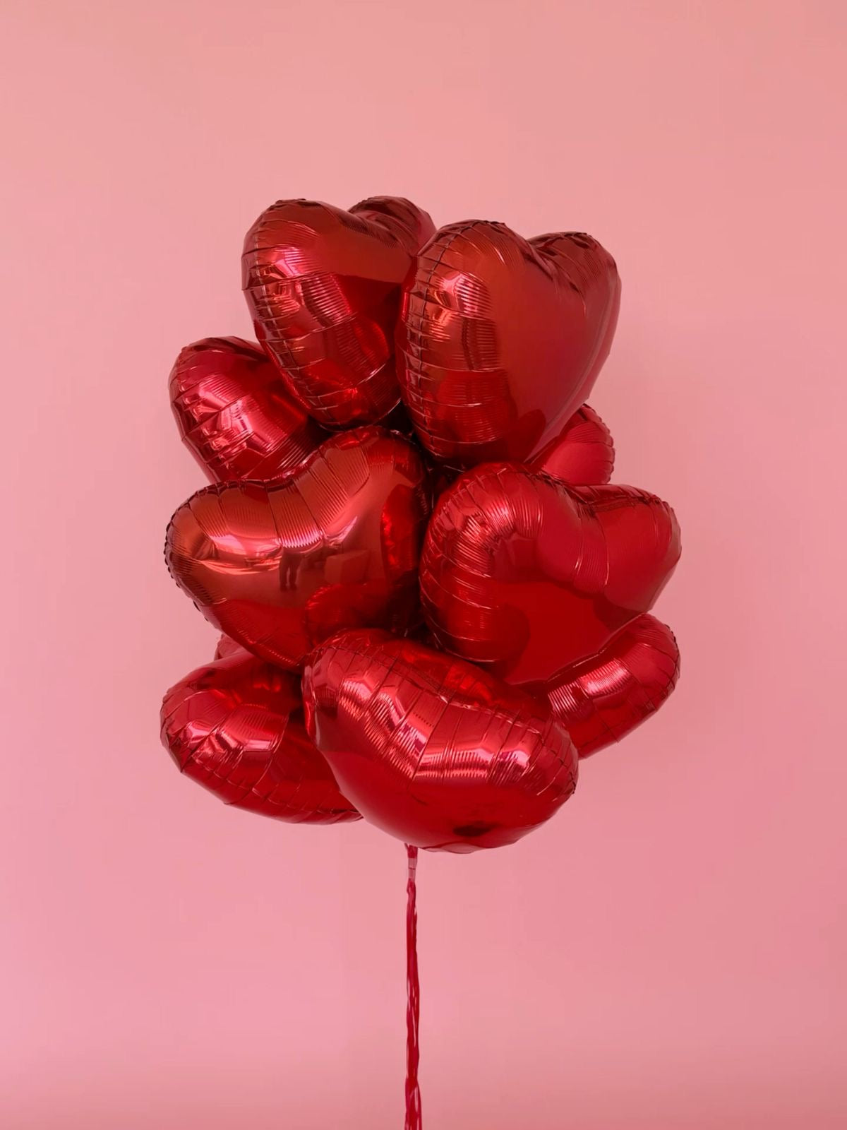 Bouquet de ballons cœur rouges love sur fond rose, photo réelle