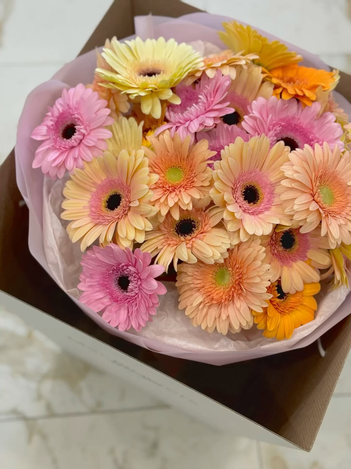 Bouquet de gerberas pêche, orange et rose dans sa boîte, version Cosette