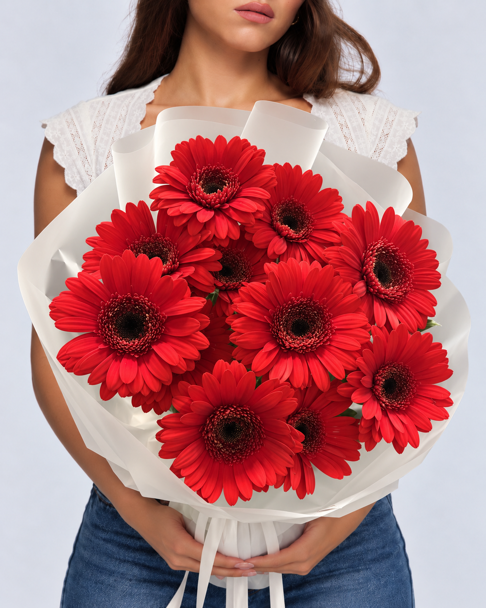 Bouquet Iman de gerberas rouges frais en papier blanc, tenu devant soi