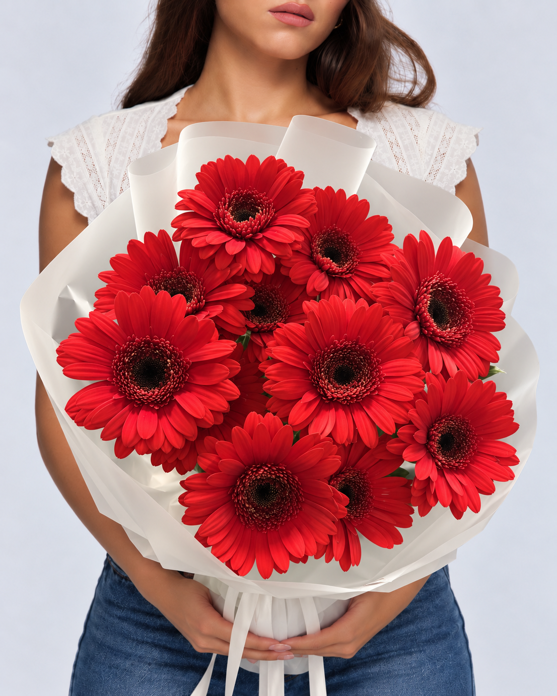 Bouquet Iman de gerberas rouges frais en papier blanc, tenu devant soi