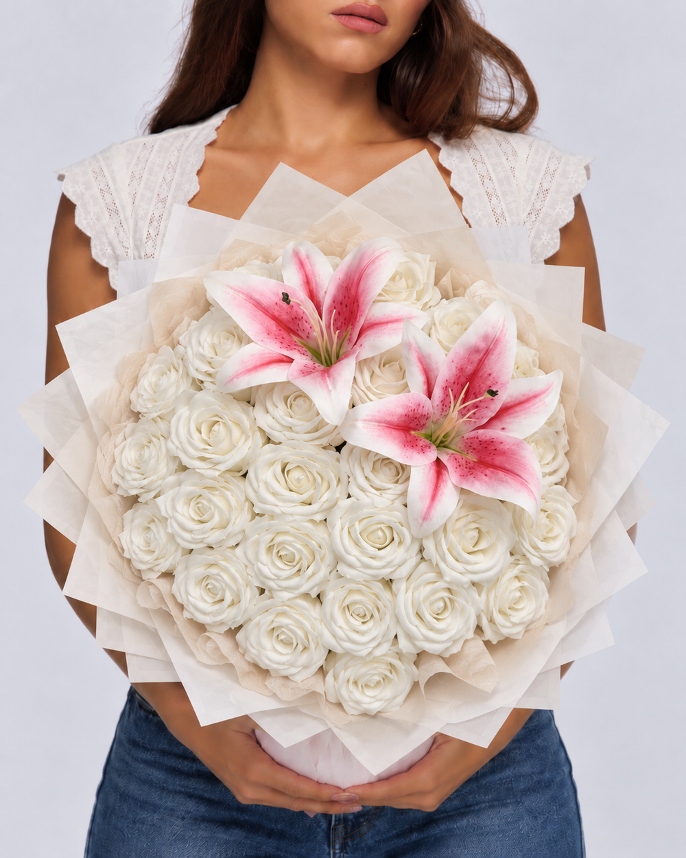 Bouquet Lilas de roses éternelles blanches et deux lys roses tenu à deux mains