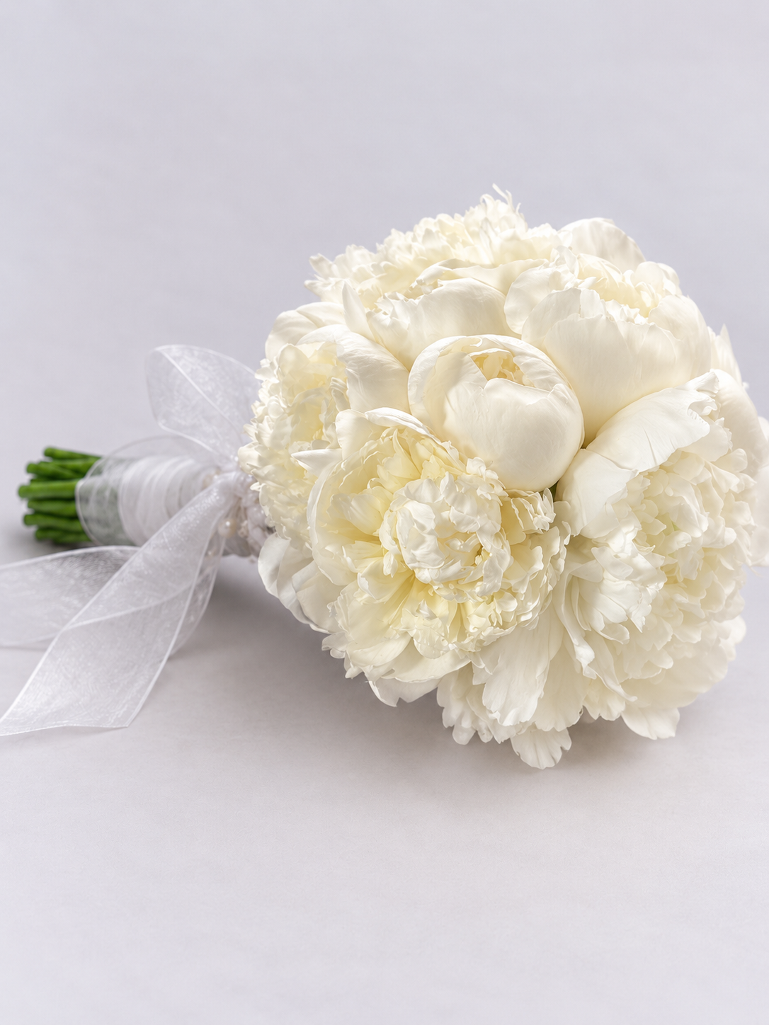 Bouquet de mariée Alba de pivoines blanches avec ruban, posé sur fond clair