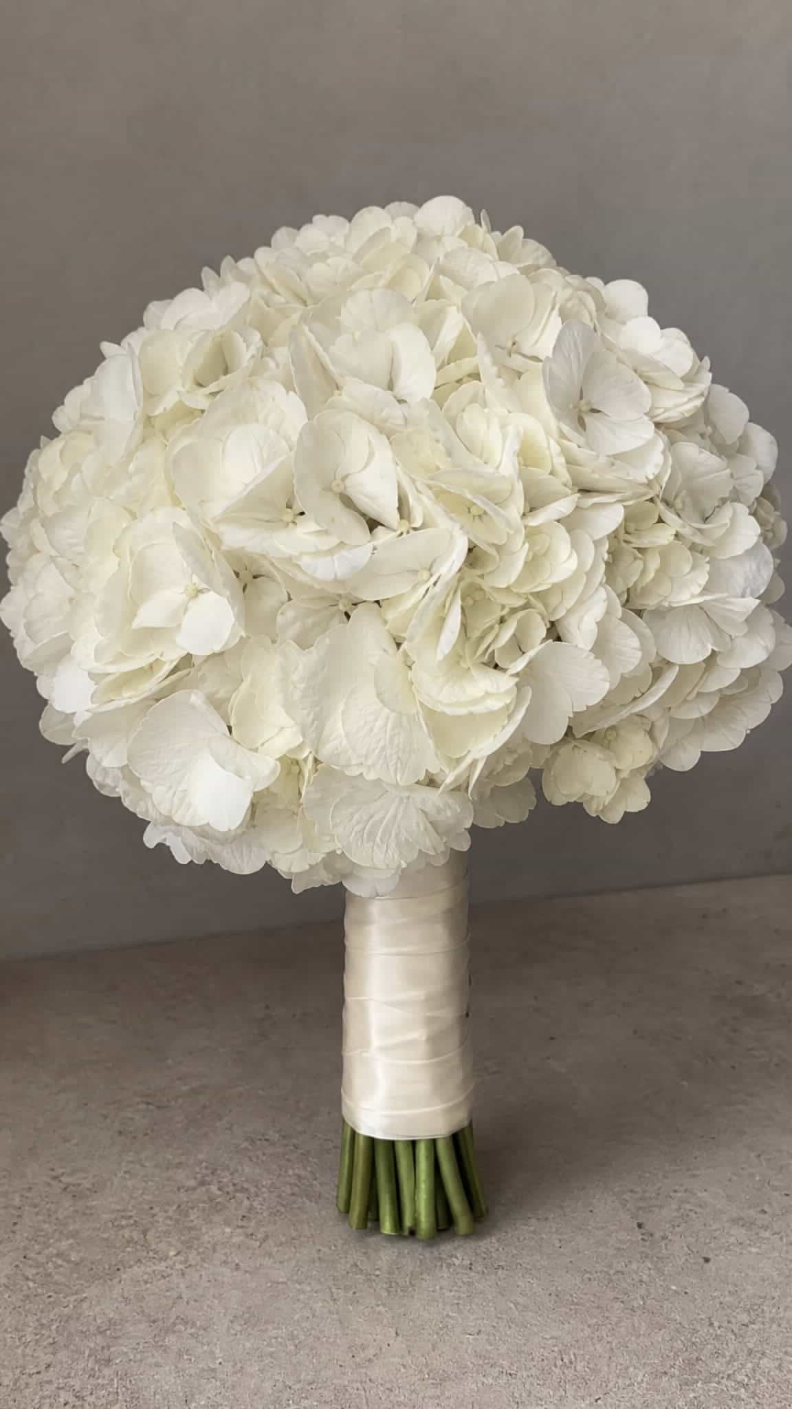 Bouquet de mariée Alexandra d'hortensias blancs aux tiges habillées d'un ruban ivoire