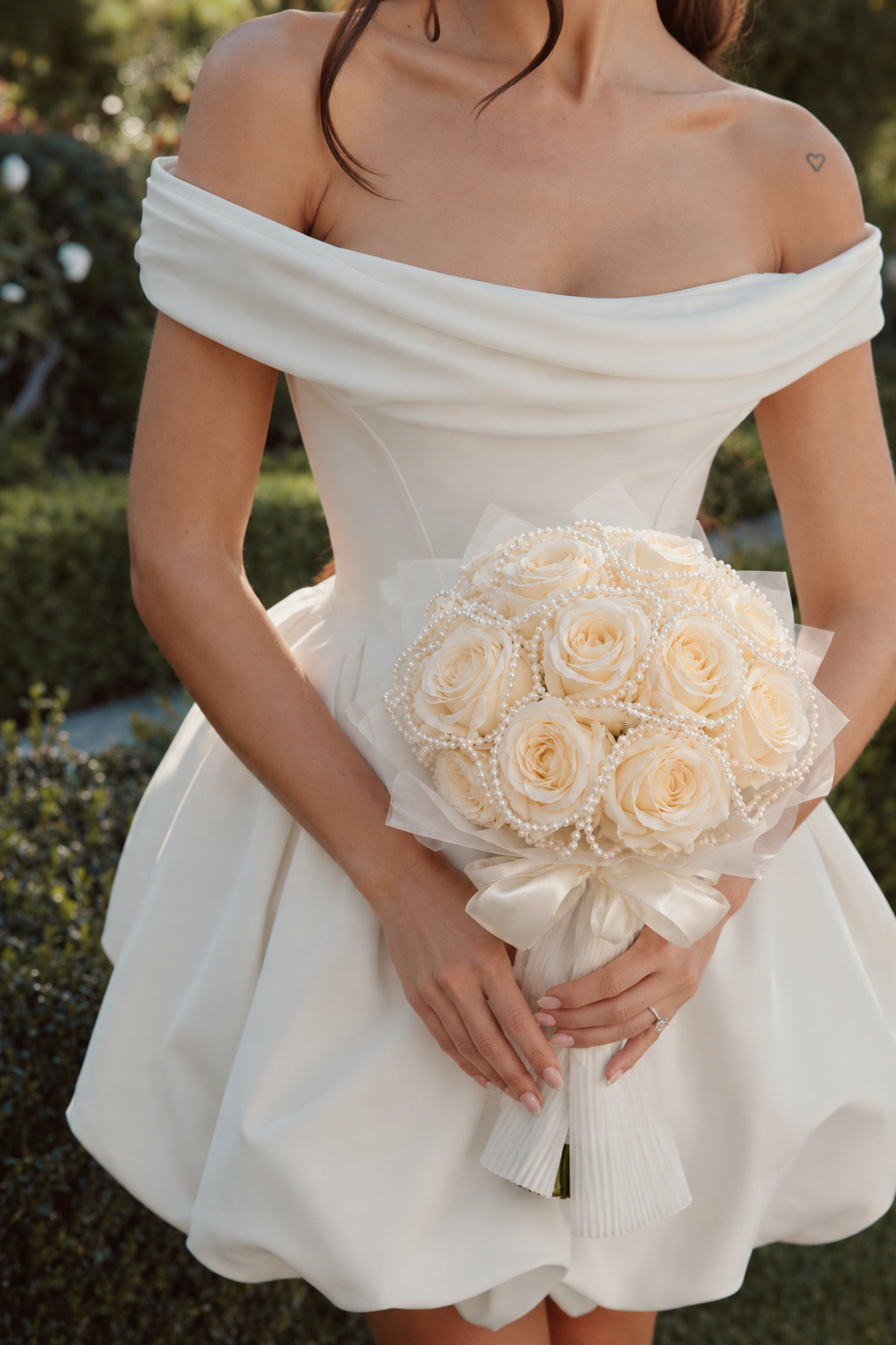 Bouquet de mariée Divas de roses artificielles crème tenu par une mariée, plan rapproché
