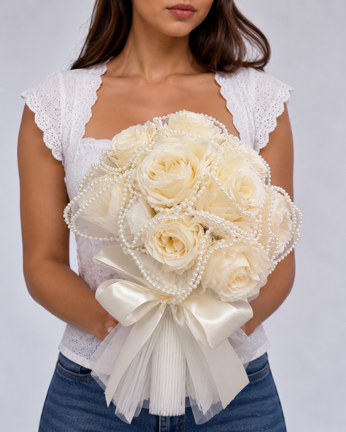 Bouquet de mariée Divas roses crème, perles et grand ruban satin ivoire, tenu à deux mains