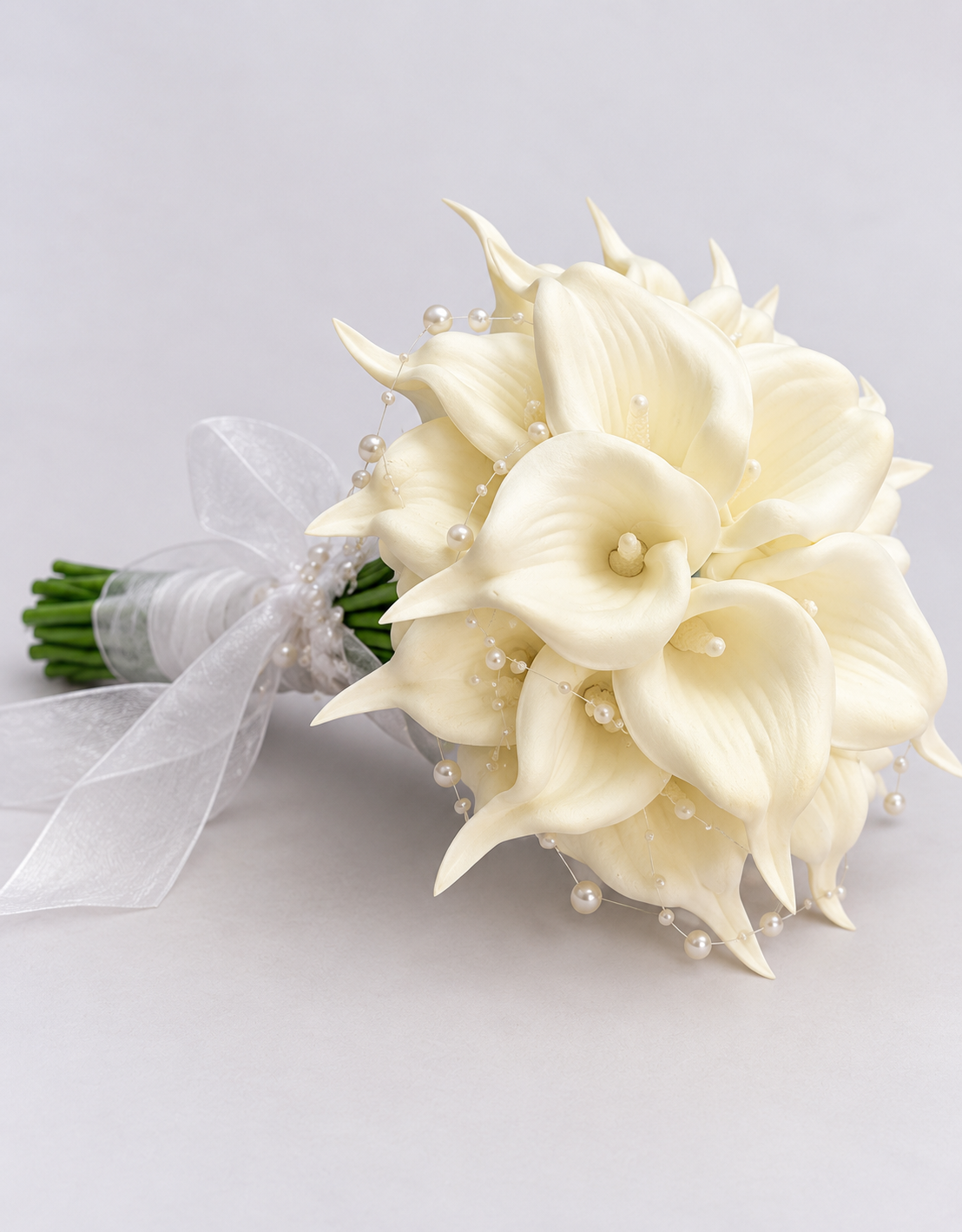 Bouquet de mariée Leonore posé de côté, arums crème, perles et tiges vertes