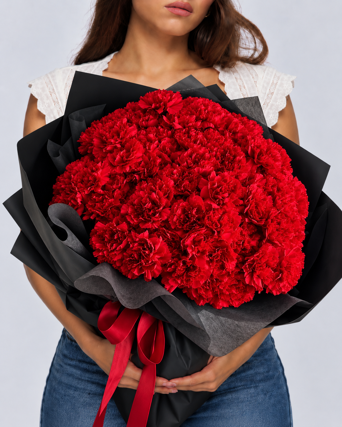 Bouquet Mimi d'œillets rouges frais en papier noir et ruban rouge, tenu devant soi