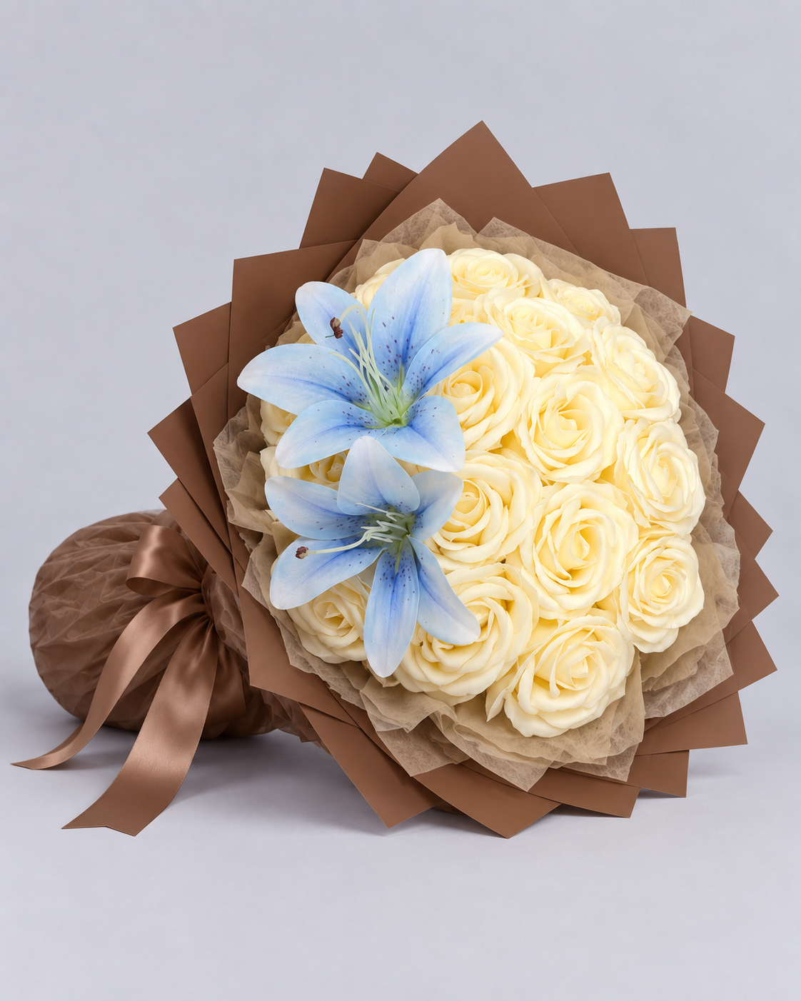 Bouquet Vaea posé de côté, roses vanille, lys bleu ciel et ruban marron