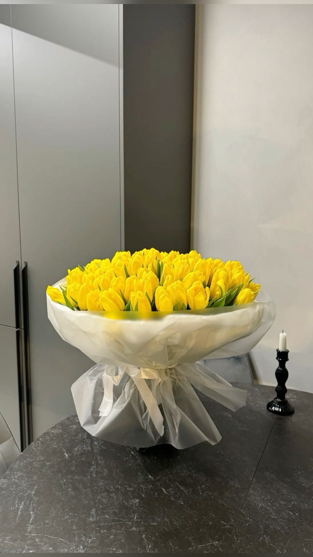 Bouquet Zoe de tulipes jaunes avec papier blanc translucide posé sur un plan de travail, photo réelle