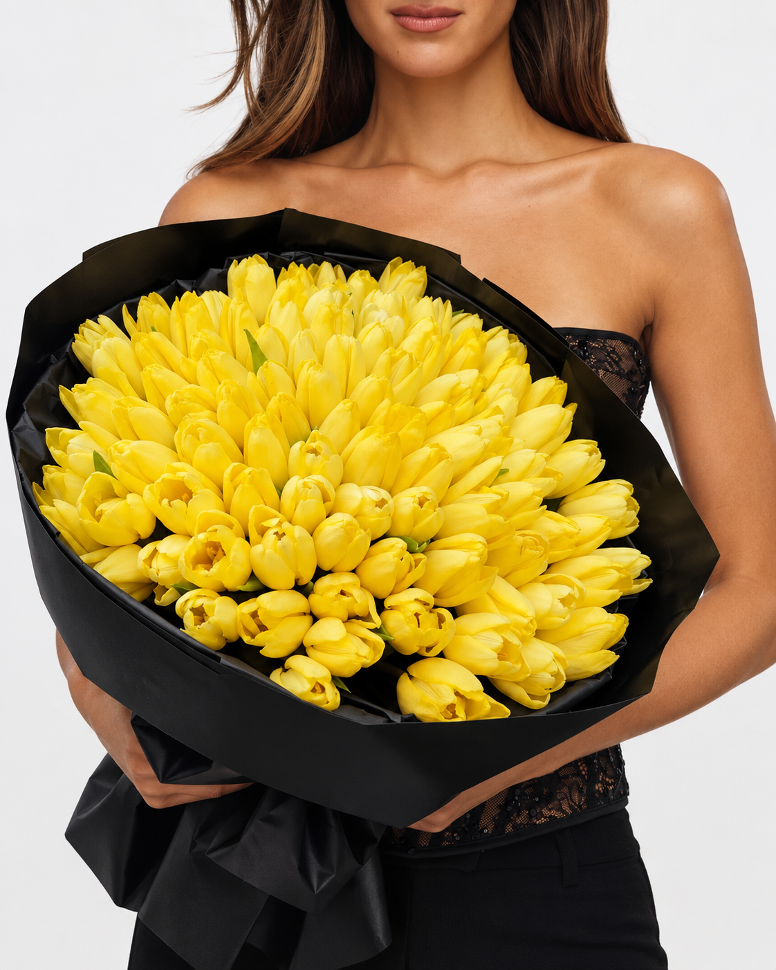 Bouquet Zoe de tulipes jaunes fraîches en papier noir, tenu devant soi