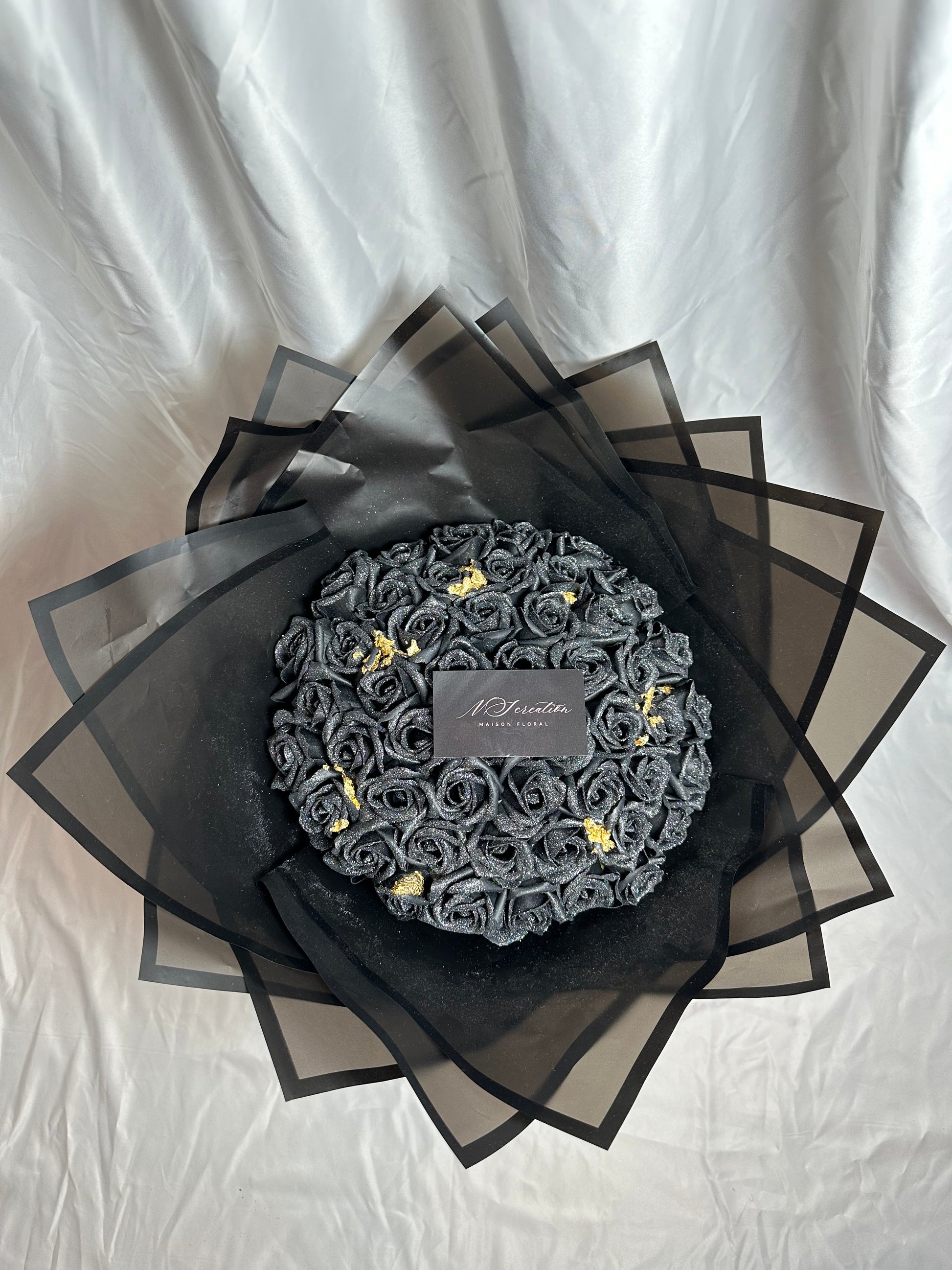 bouquet de roses noirs scintillants avec feuille d'or et emballage noir