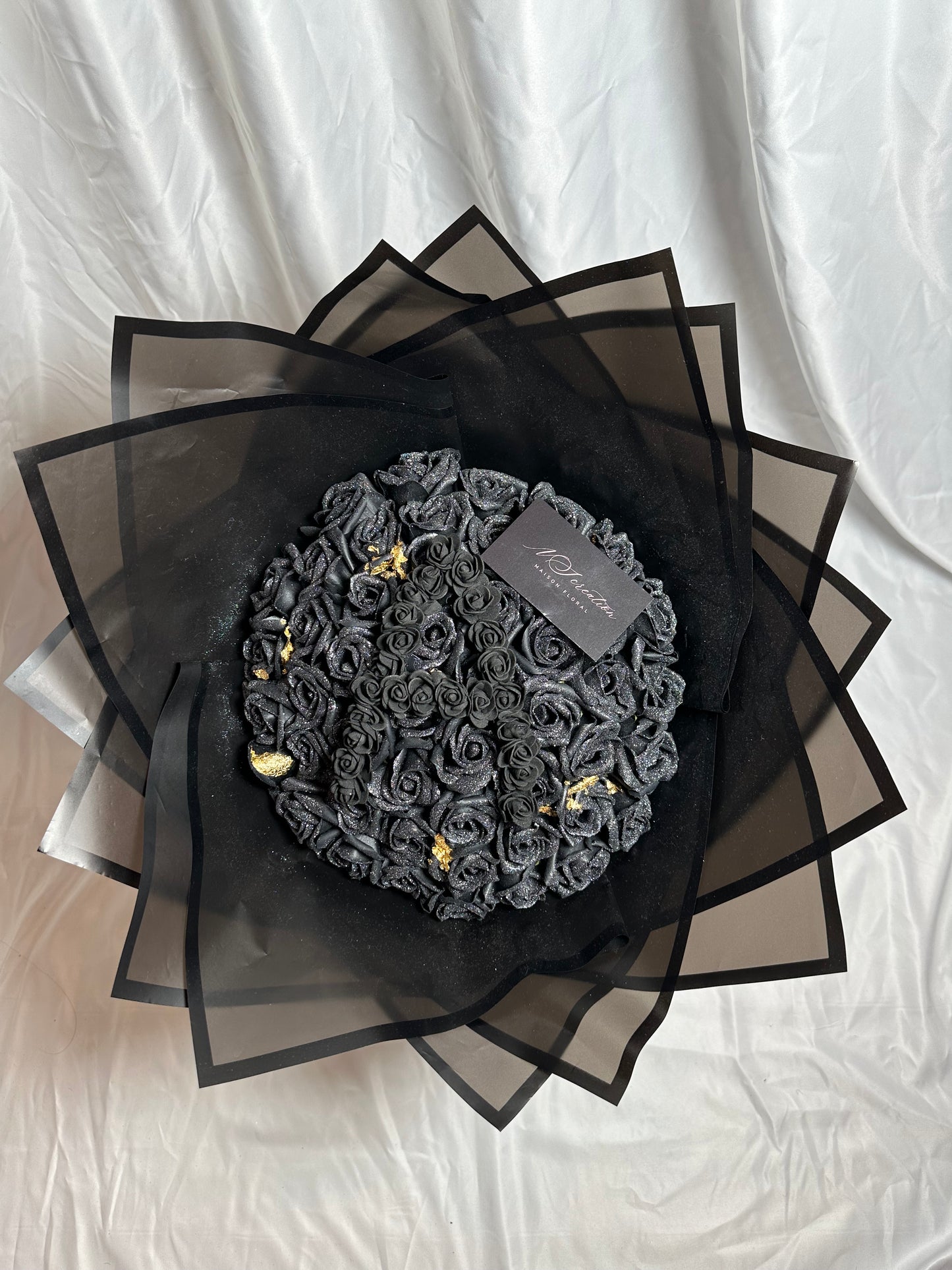 bouquet de roses noirs scintillants avec feuille d'or et emballage noir avec une lettre en noir