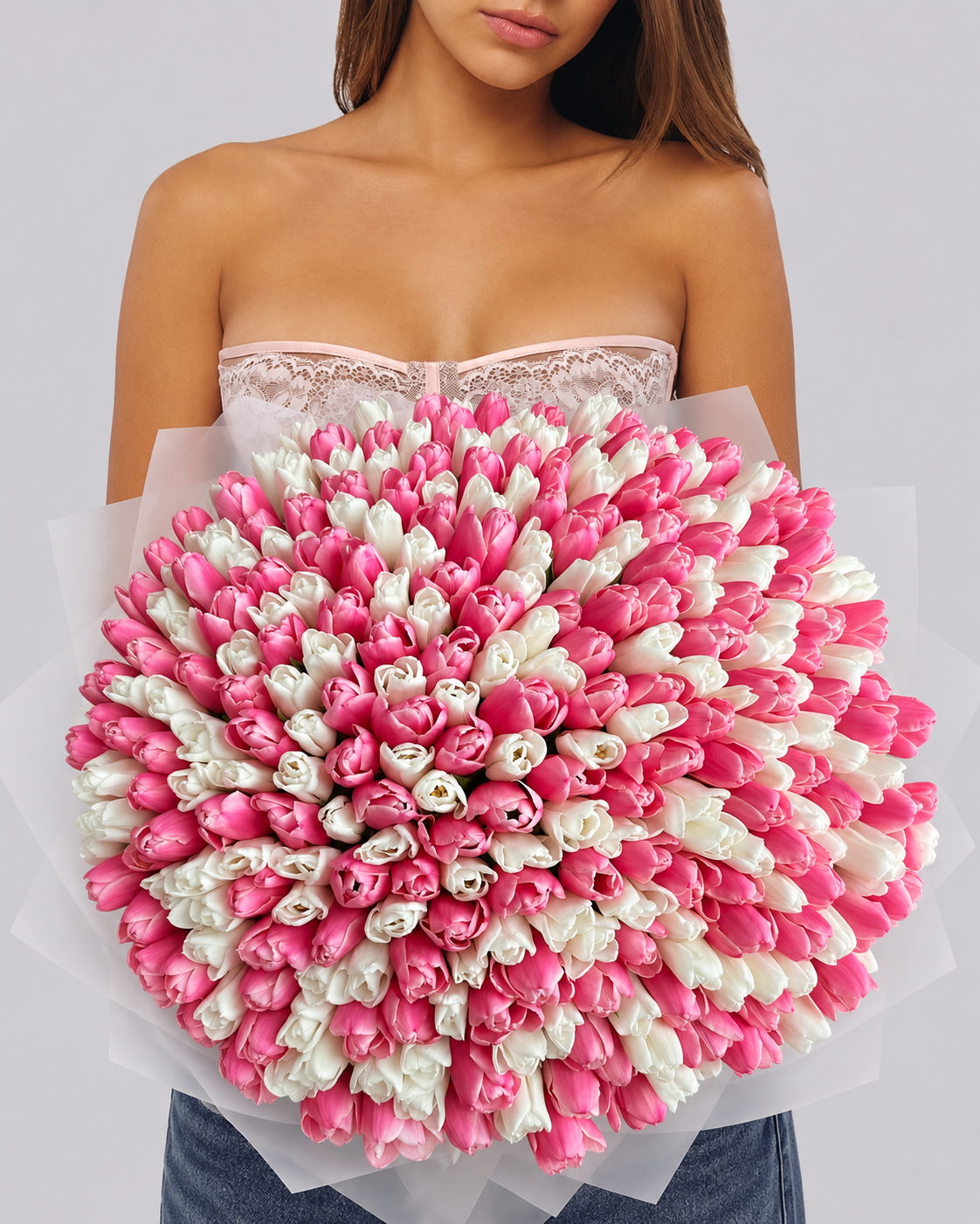 Bouquet Cadie de tulipes roses et blanches fraîches porté par une femme, vue de face