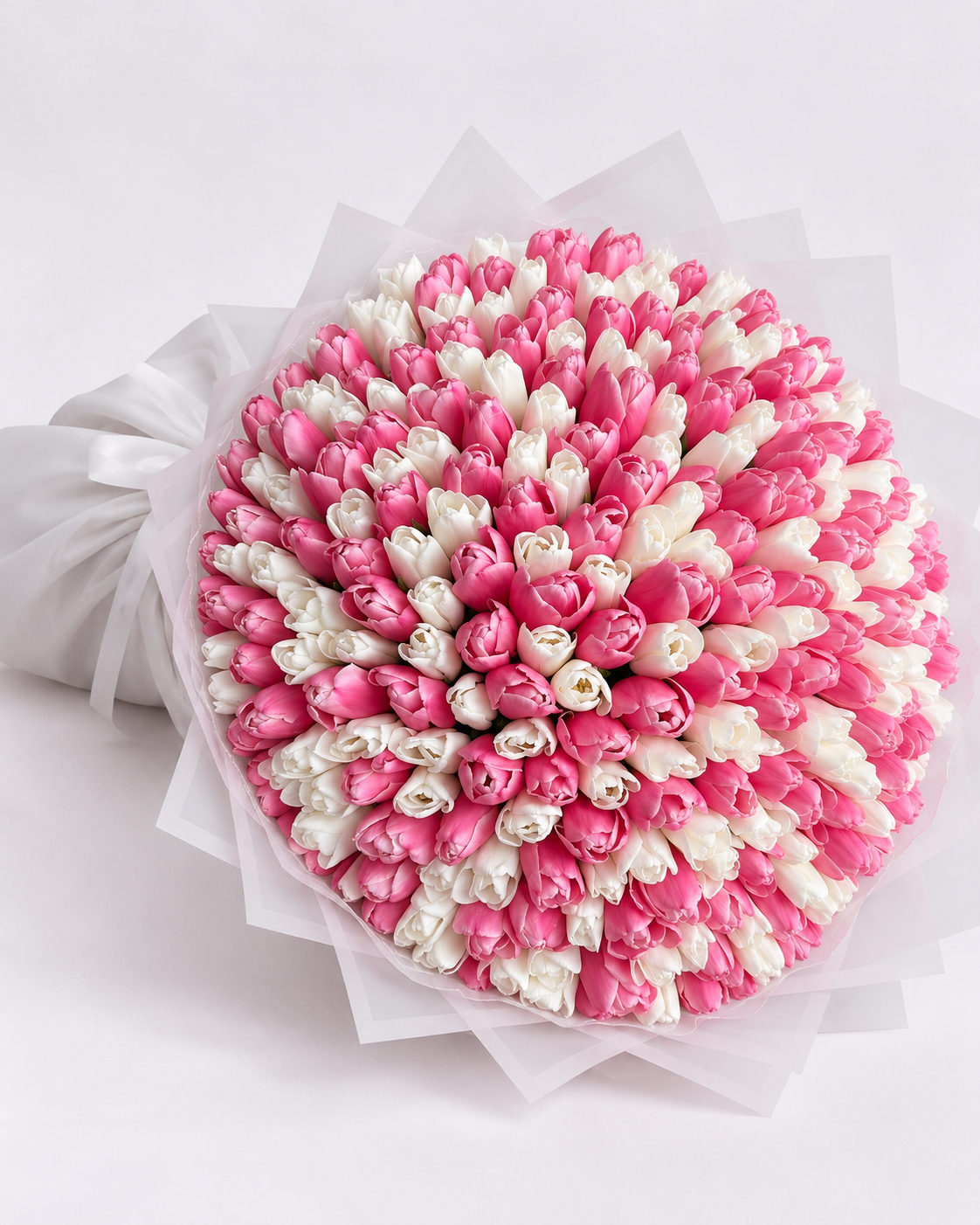 Bouquet Cadie de tulipes roses et blanches posé sur fond clair, papier blanc