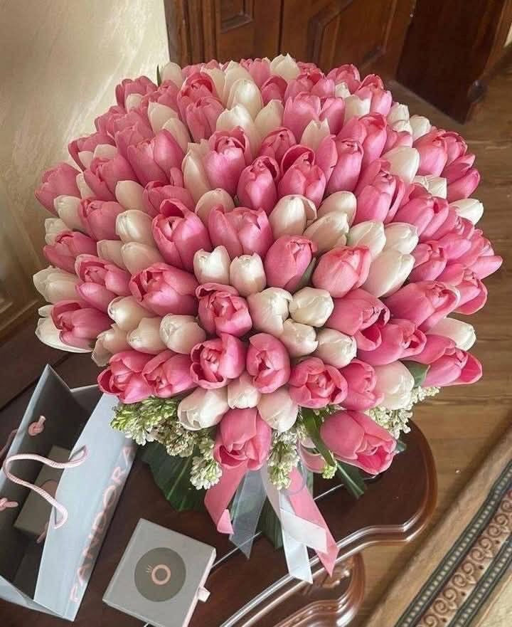Bouquet Cadie de tulipes roses et blanches posé sur une table avec ruban