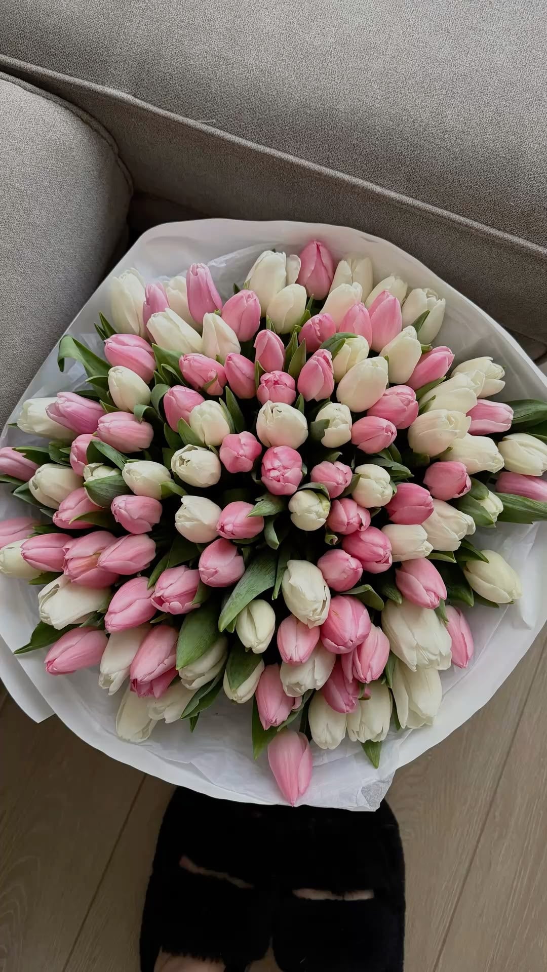 Bouquet Cadie de tulipes roses et blanches posé sur un canapé clair, vue de dessus