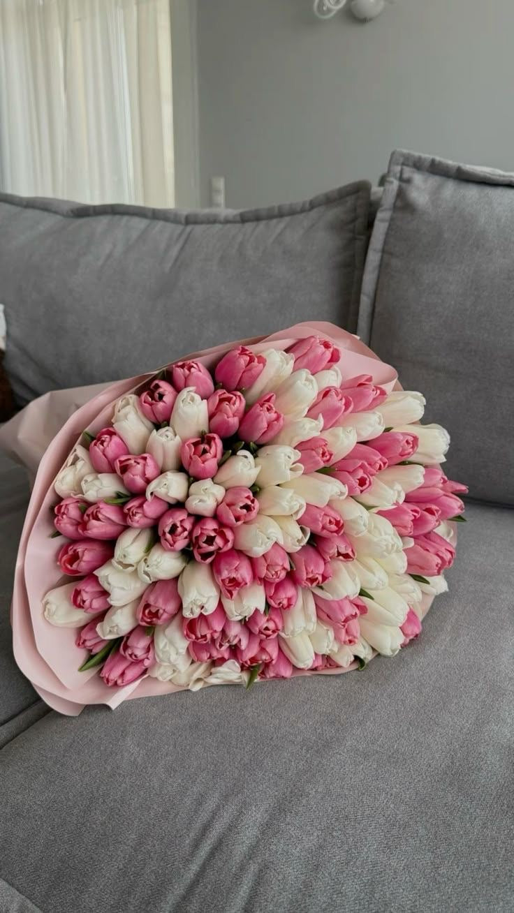 Bouquet Cadie de tulipes roses et blanches posé sur un canapé gris