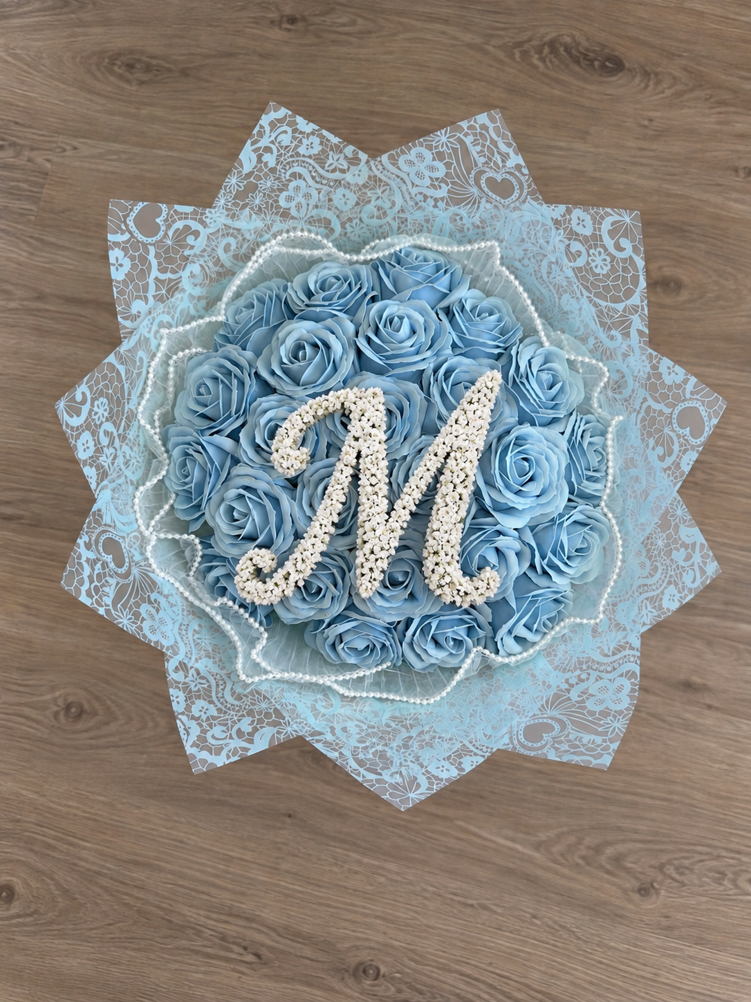Bouquet CENDRILLON de 25 roses éternelles bleu ciel posé sur un fond bois