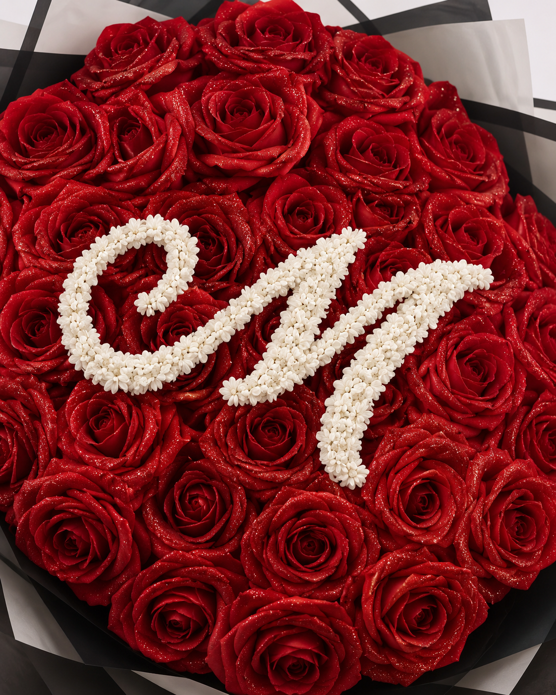 Gros plan sur les roses éternelles rouges et la lettre perlée du bouquet CHIRA