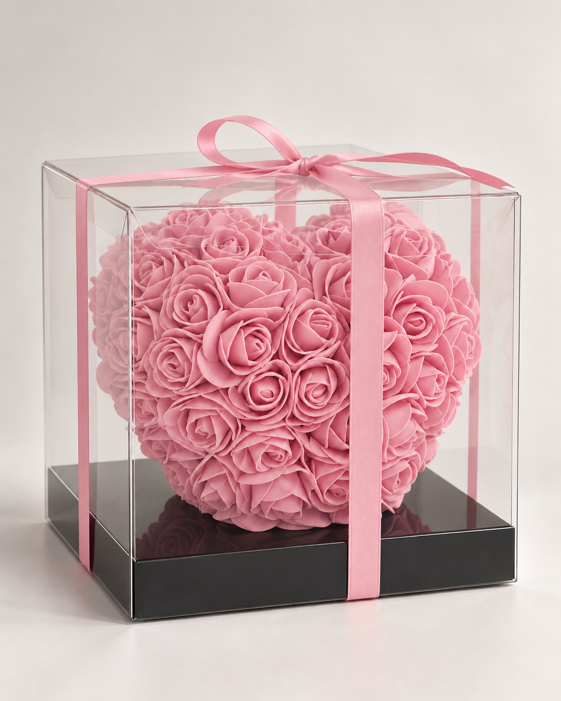 Cœur de roses éternelles roses sous boîte transparente, ruban rose et socle noir, autre angle