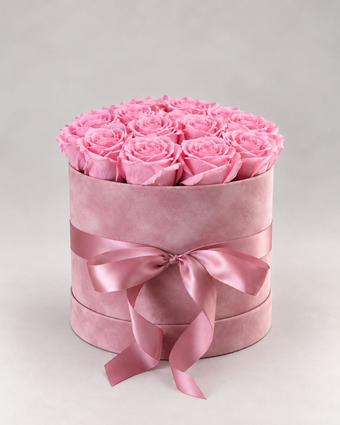 Coffret Petit Bonheur, roses éternelles roses dans un coffret rond en velours rose noué d'un ruban