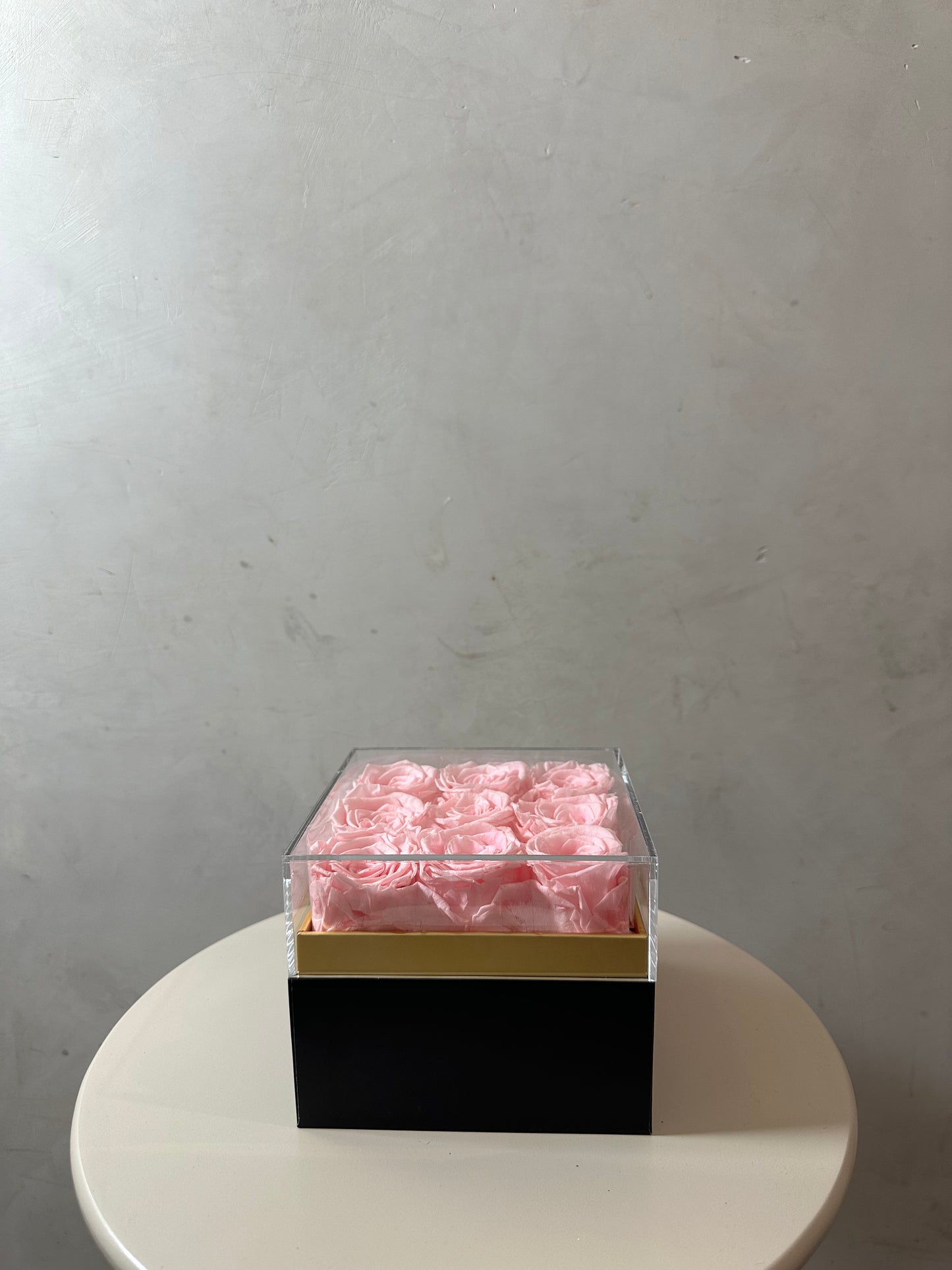  coffret de fleurs Flora, contenant 9 roses éternelles rose. Le coffret transparent en acrylique met en valeur ces fleurs intemporelles