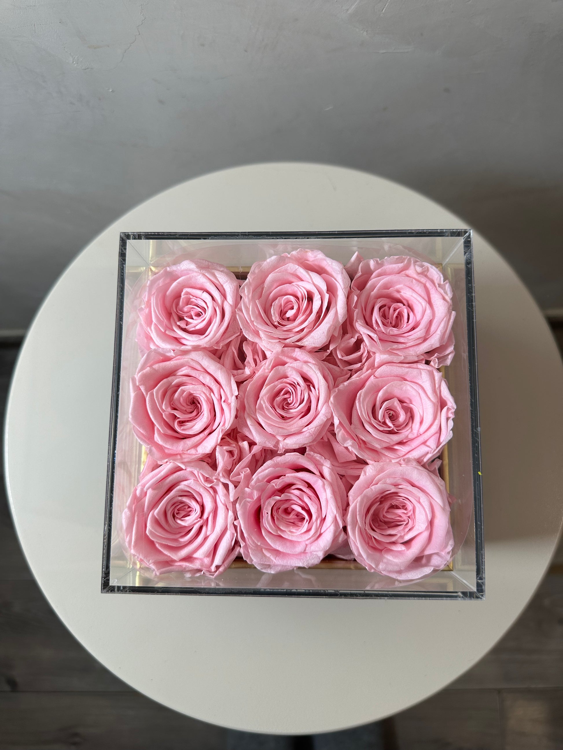  coffret de fleurs Flora, contenant 9 roses éternelles rose. Le coffret transparent en acrylique met en valeur ces fleurs intemporelles