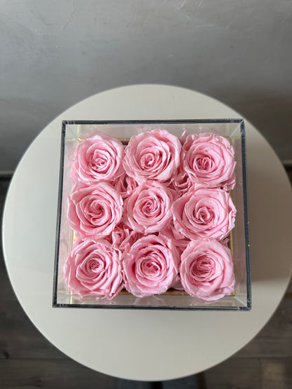  coffret de fleurs Flora, contenant 9 roses éternelles rose. Le coffret transparent en acrylique met en valeur ces fleurs intemporelles
