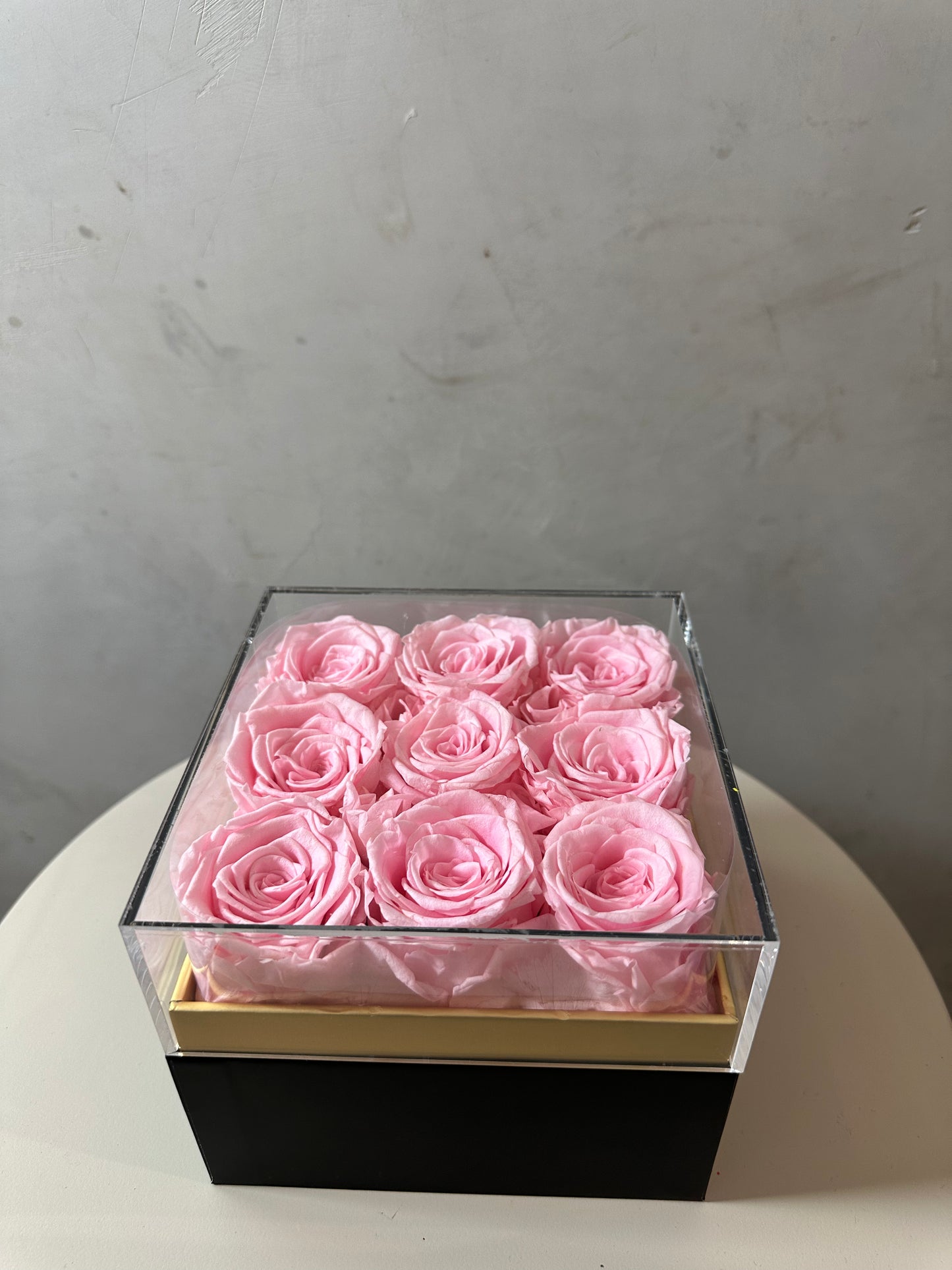  coffret de fleurs Flora, contenant 9 roses éternelles rose. Le coffret transparent en acrylique met en valeur ces fleurs intemporelles