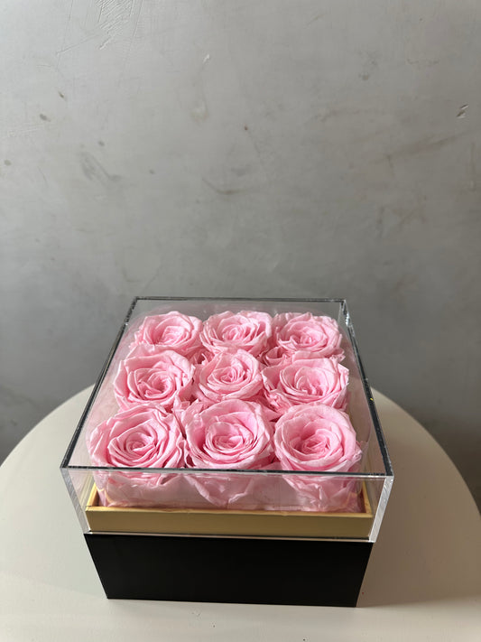  coffret de fleurs Flora, contenant 9 roses éternelles rose. Le coffret transparent en acrylique met en valeur ces fleurs intemporelles