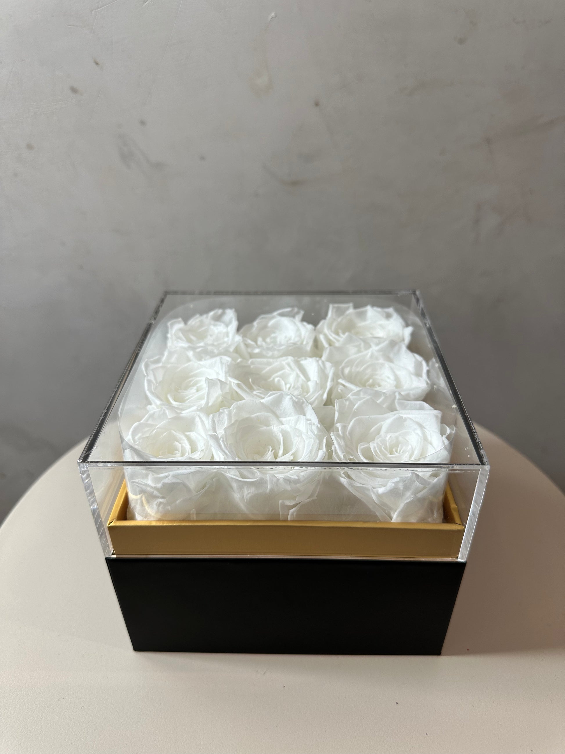  coffret de fleurs Innocente, contenant 9 roses éternelles blanches. Le coffret transparent en acrylique 