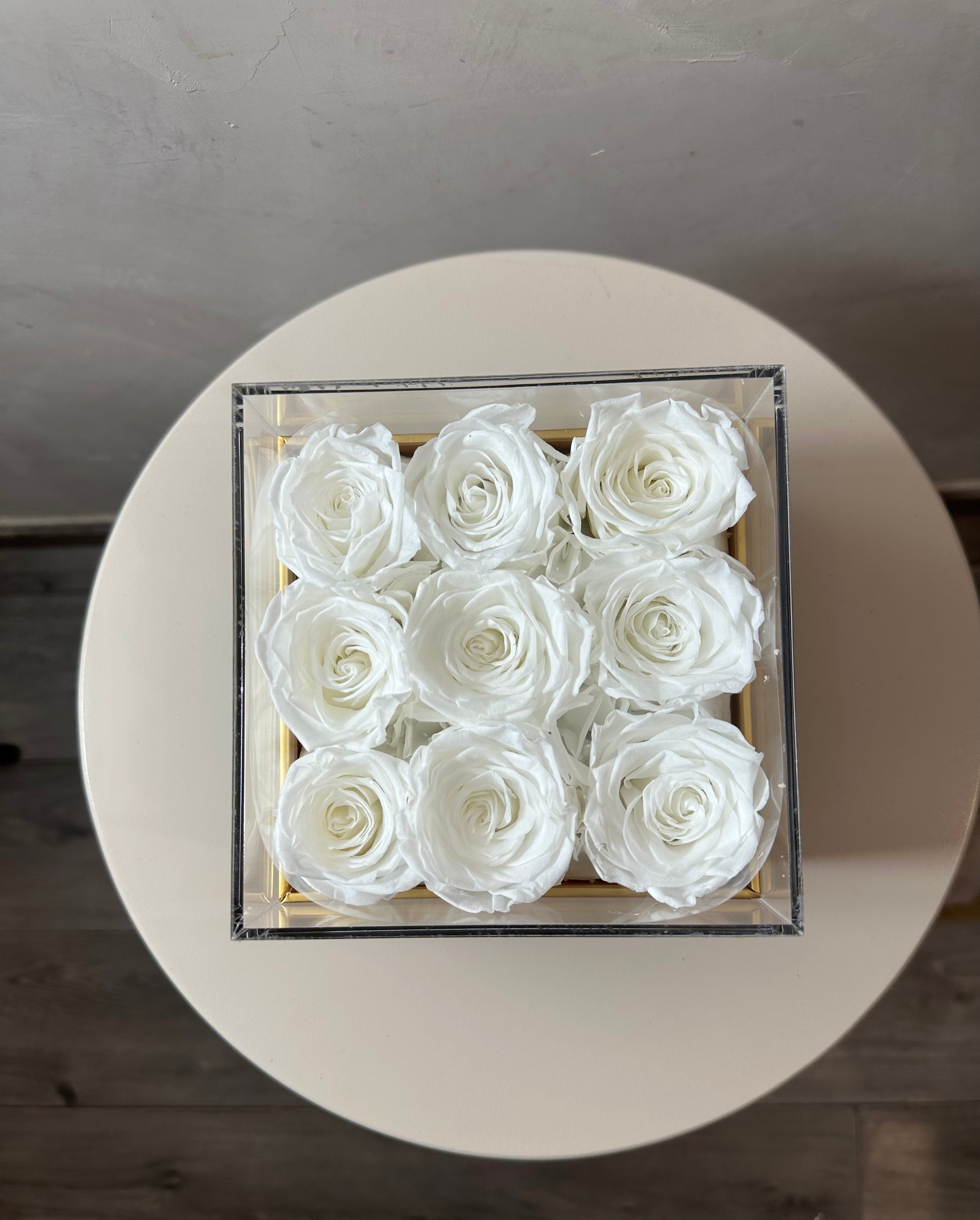  coffret de fleurs Innocente, contenant 9 roses éternelles blanches. Le coffret transparent en acrylique 