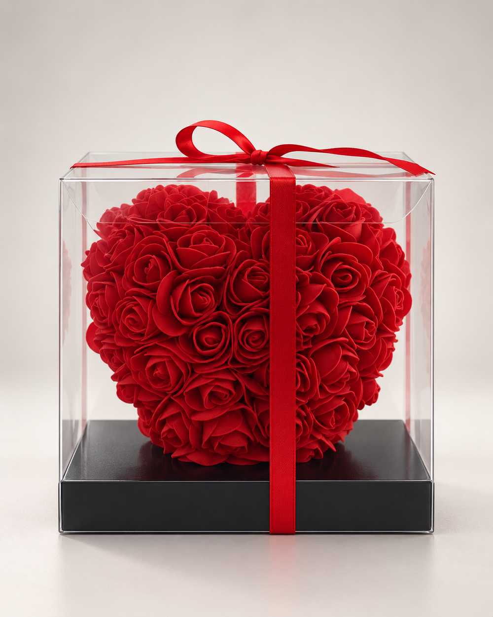 Coup de cœur fleuri, cœur de roses artificielles rouges dans une boîte transparente avec ruban rouge, vue de face