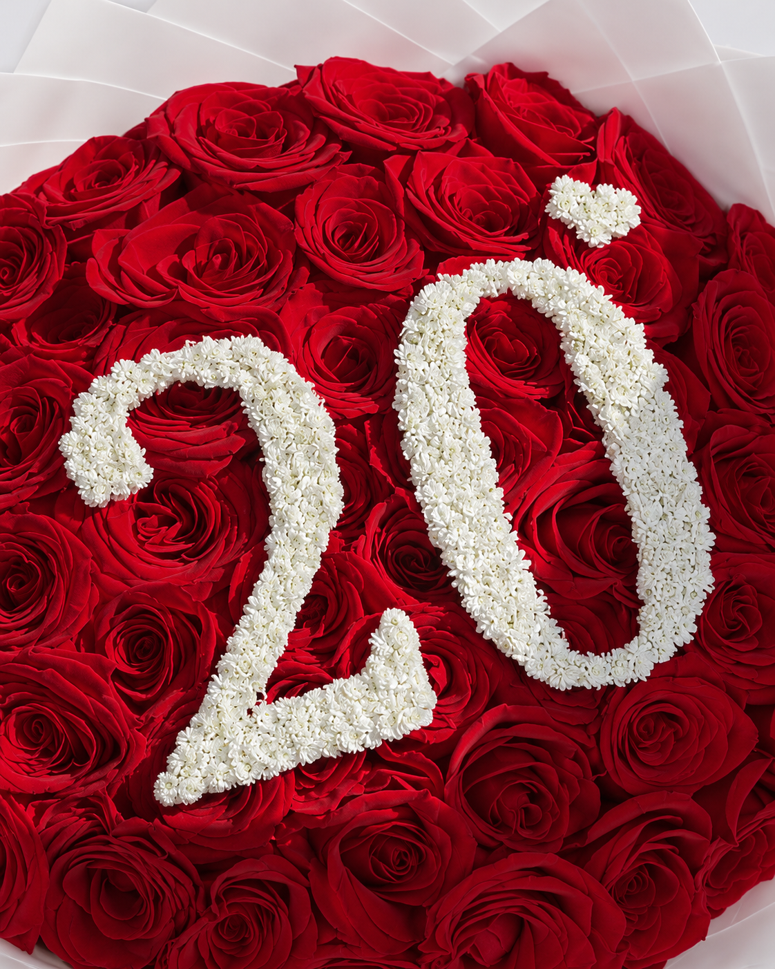 Gros plan sur le chiffre 20 blanc au centre des roses rouges du bouquet Demi