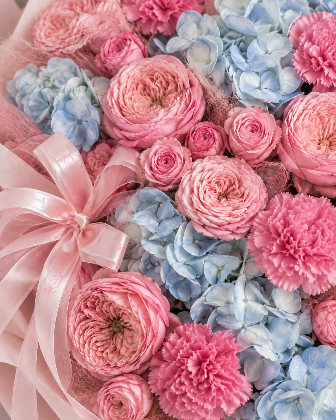 Gros plan sur les hortensias bleus, œillets roses et renoncules du bouquet DOROTHÉ