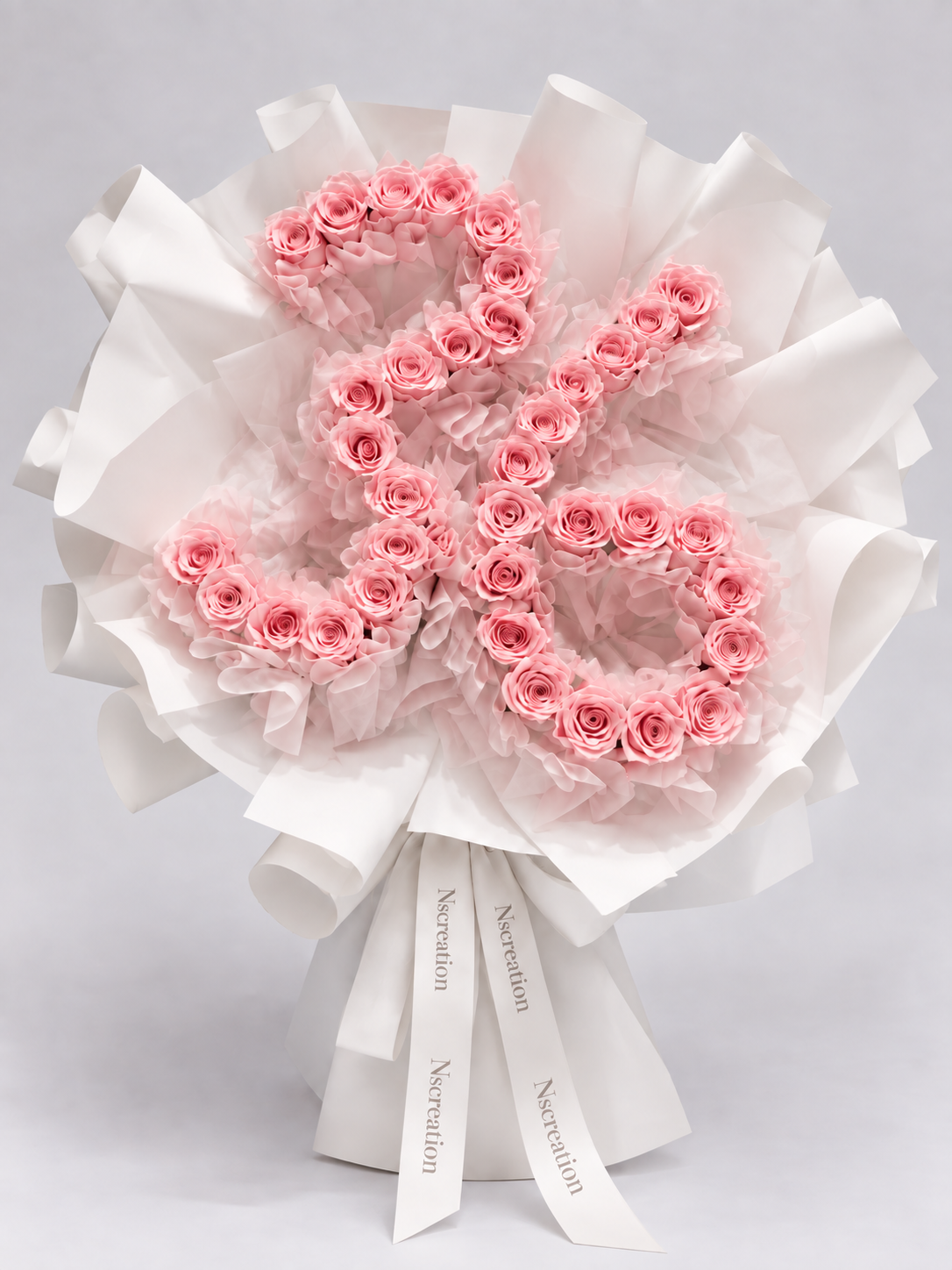 Bouquet Elana de roses roses en forme de chiffre posé sur fond clair, vue de côté