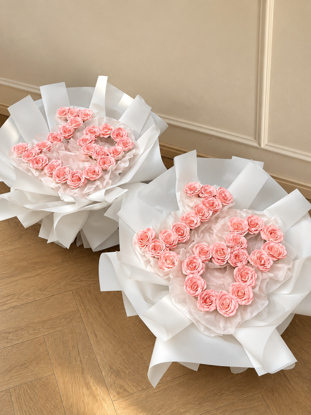 Deux bouquets Elana de roses roses en forme de chiffre posés sur un parquet