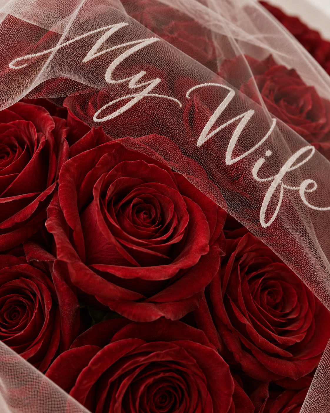 Gros plan sur les roses rouges fraîches et le message sur le tulle du bouquet JANNA