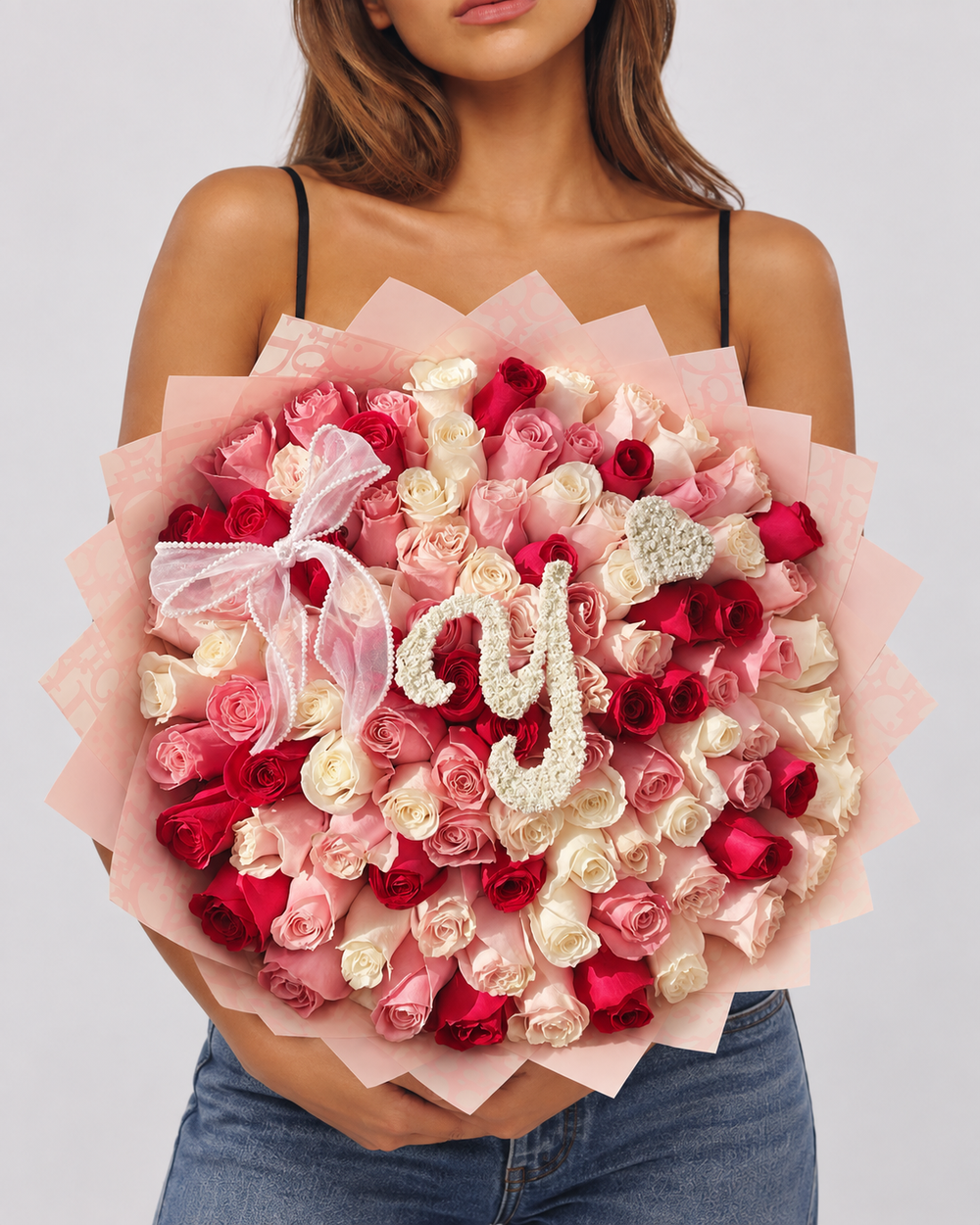 Bouquet Juliette de roses fraîches rouges, roses et blanches avec lettre décorative, porté par une femme