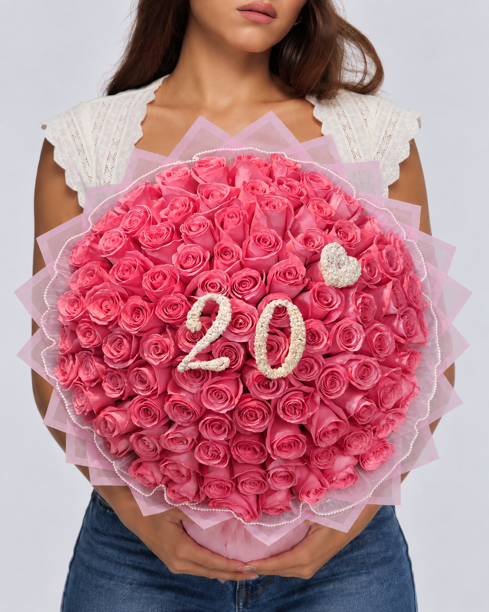 Bouquet Kikky de roses rose vif fraîches avec chiffre 20 blanc, porté par une femme